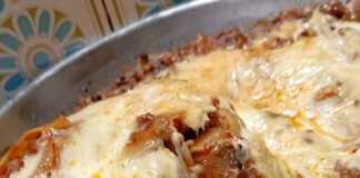 Ένα βαθύ τηγάνι γεμάτο με λαζάνια, πλούσιο κιμά και λιωμένα κίτρινα τυριά που αχνίζουν.