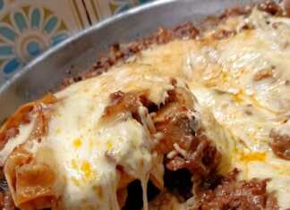 Ένα βαθύ τηγάνι γεμάτο με λαζάνια, πλούσιο κιμά και λιωμένα κίτρινα τυριά που αχνίζουν.