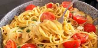 Ένα βαθύ τηγάνι γεμάτο με σπαγγέτι, κομμάτια κοτόπουλου, λιωμένο τυρί και ζουμερά ντοματίνια, πασπαλισμένο με φρέσκο μαϊντανό.