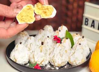 Μικρά αμυγδαλωτά σε σχήμα μανταρινιού, πασπαλισμένα με άχνη ζάχαρη και στολισμένα με ένα γαρύφαλλο στην κορυφή, τοποθετημένα σε πιατέλα.