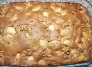 Μια ζουμερή μηλόπιτα σε πυρέξ, στολισμένη με ολόκληρα καρύδια στην επιφάνεια και περιχυμένη με χρυσάφι σιρόπι.