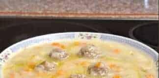 Ένα βαθύ πιάτο με ζεστή σούπα γιουβαρλάκια σε μέγεθος μίνι, περιτριγυρισμένα από πολύχρωμα κυβάκια καρότου, πατάτας και κολοκυθιού.