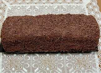 Ένας λαχταριστός κορμός σοκολάτας πασπαλισμένος με τρούφα και νουτέλα, κομμένος σε φέτες που δείχνουν τα λευκά κομμάτια μπισκότου στο εσωτερικό του.