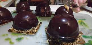 Κομψά ατομικά γλυκά μους καραμέλας καλυμμένα με γυαλιστερή επικάλυψη σοκολάτας, τοποθετημένα σε μια πιατέλα σερβιρίσματος.