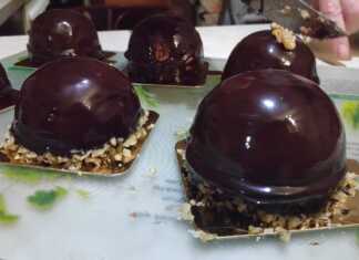 Κομψά ατομικά γλυκά μους καραμέλας καλυμμένα με γυαλιστερή επικάλυψη σοκολάτας, τοποθετημένα σε μια πιατέλα σερβιρίσματος.