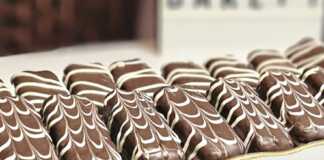 Σαντουιτσάκια Σοκολάτας Γεμιστά: Η Απόλυτη Λύση για Γρήγορο και Εντυπωσιακό Γλυκό! Σειρές από μικρά σαντουιτσάκια μπισκότου καλυμμένα με σοκολάτα γάλακτος και διακοσμημένα με γραμμές λευκής σοκολάτας.