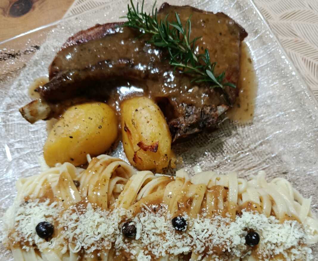 Μια ζουμερή χοιρινή μπριζόλα δίπλα σε τραγανή πατάτα, καλυμμένη με μια βελούδινη σάλτσα κρασιού και λεμονιού, σερβιρισμένη με ζυμαρικά.