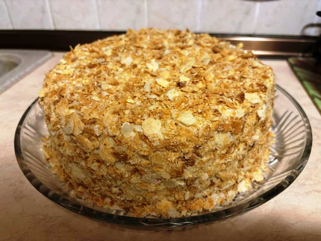 Μια εντυπωσιακή τούρτα Ναπολέων με πολλές λεπτές στρώσεις σφολιάτας, καλυμμένη με πλούσια κρέμα και τριμμένο φύλλο περιμετρικά.