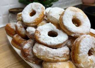 Μια στοίβα από φουσκωτά, χρυσαφένια ντόνατς, πλούσια πασπαλισμένα με λευκή ζάχαρη άχνη μέσα σε ένα βαθύ μπολ.