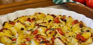 Πατάτες στο Φούρνο με Μοτσαρέλα: Μια Διαφορετική και Πεντανόστιμη Απόλαυση! Ένα ταψί με ροδοκοκκινισμένες πατάτες φούρνου, καραμελωμένα κρεμμύδια και ψημένα ντοματίνια, καλυμμένα με πλούσια λιωμένη μοτσαρέλα.