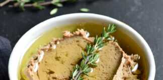 Ένα μικρό κεραμικό δοχείο με πατέ συκωτιού, καλυμμένο με μια στρώση χρυσαφένιου λιωμένου βουτύρου και ένα κλαδάκι θυμάρι από πάνω.