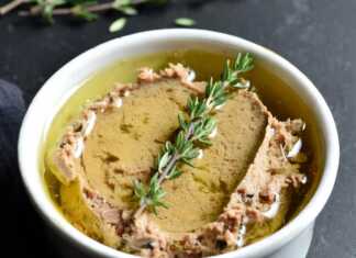 Ένα μικρό κεραμικό δοχείο με πατέ συκωτιού, καλυμμένο με μια στρώση χρυσαφένιου λιωμένου βουτύρου και ένα κλαδάκι θυμάρι από πάνω.