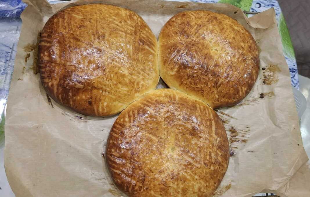 Στρογγυλές χρυσαφένιες πίτες με παραδοσιακά σχέδια από πιρούνι στην επιφάνεια, τοποθετημένες σε λαδόκολλα.