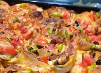 Μια σειρά από πιτσάκια σε σχήμα ρολού μέσα σε ταψί, με λιωμένο τυρί, σάλτσα ντομάτας και κομμάτια ζαμπόν να ξεχειλίζουν.