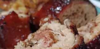 Ένα καλοψημένο ρολό χοιρινής πανσέτας με χρυσαφένια τραγανή πέτσα, δεμένο με σπάγκο και σερβιρισμένο με πατάτες φούρνου.