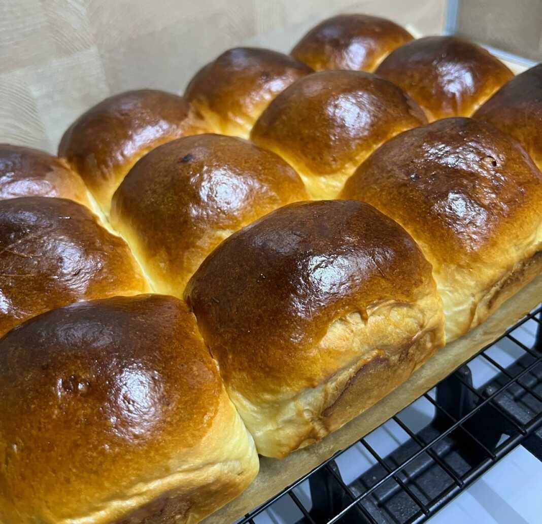 Ένα ταψί γεμάτο με ροδοκόκκινα, αφράτα στρογγυλά ψωμάκια που μόλις βγήκαν από τον φούρνο.