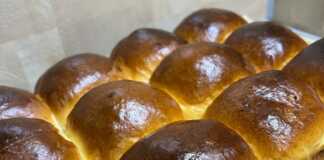 Ψωμάκια “Αφρός”: Η Γεύση της Παιδικής μας Ηλικίας! Ένα ταψί γεμάτο με ροδοκόκκινα, αφράτα στρογγυλά ψωμάκια που μόλις βγήκαν από τον φούρνο.