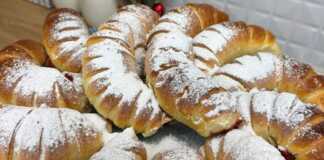 Σειρές από χρυσαφένια, φουσκωτά κρουασανάκια πασπαλισμένα με άχνη ζάχαρη, με την κόκκινη γέμιση βύσσινου να ξεπροβάλλει ελαφρώς.