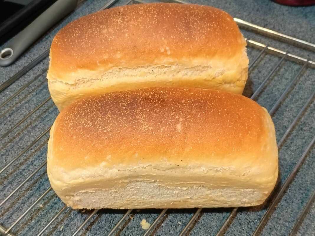 Ένα καρβέλι σταρένιο ψωμί φόρμας με χρυσαφένια κρούστα, τοποθετημένο πάνω σε ξύλινη επιφάνεια.