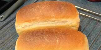 Ένα καρβέλι σταρένιο ψωμί φόρμας με χρυσαφένια κρούστα, τοποθετημένο πάνω σε ξύλινη επιφάνεια.