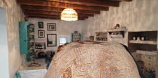 Ένα μεγάλο χωριάτικο ψωμί με χρυσαφένια τραγανή κόρα, τοποθετημένο πάνω σε μια βαμβακερή πετσέτα, κομμένο σε φέτες που δείχνουν την πλούσια ψίχα του.