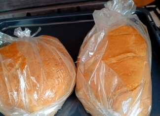 2 καρβέλια σπιτικό ψωμί με χρυσαφένια τραγανή κρούστα και βαθιά σκισίματα στην κορυφή, τοποθετημένο σε σακούλα