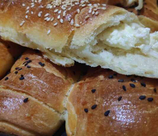 Σειρές από χρυσαφένια, αφράτα ρολάκια με τυρί, πασπαλισμένα με σουσάμι, μόλις βγήκαν από τον φούρνο.