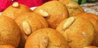 Μια πιατέλα με στρογγυλά σιροπιαστά σεκέρ παρέ, το καθένα διακοσμημένο με ένα ολόκληρο ασπρισμένο αμύγδαλο στο κέντρο.