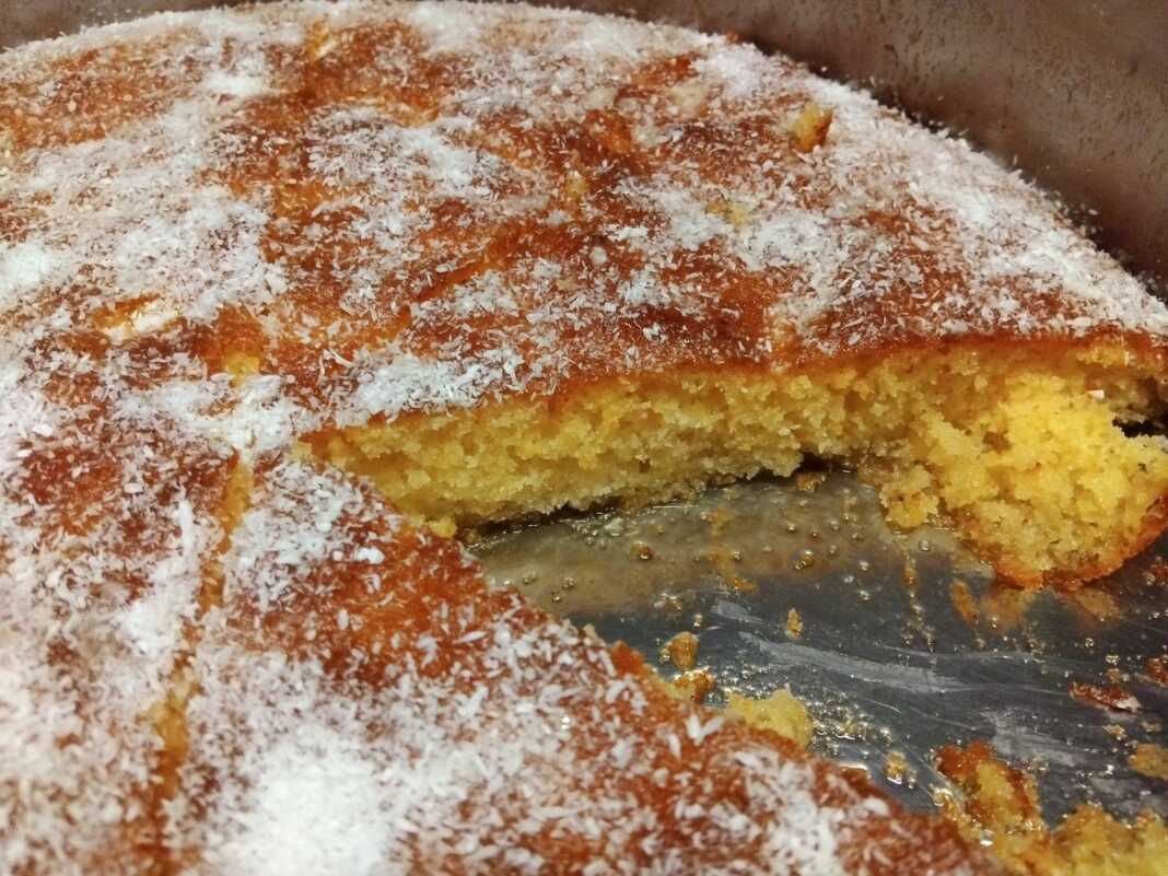 Ένα ταψί με κομμένα τετράγωνα κομμάτια ραβανί, καλά σιροπιασμένα και γαρνιρισμένα με ξύσμα λεμονιού.