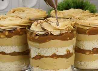 Πέντε ποτήρια γεμάτα με στρώσεις Snickers Trifle, διακοσμημένα με ροζέτες κρέμας, λιωμένη σοκολάτα και κομμάτια σοκολάτας Snickers.