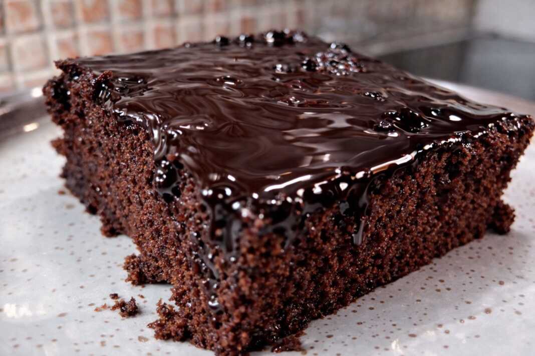 Ένα κομμάτι ζουμερής σοκολατόπιτας με γυαλιστερό σιρόπι σοκολάτας να τρέχει στις πλευρές του, σερβιρισμένο σε ένα πιάτο.