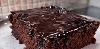 Σοκολατόπιτα Χωρίς Μίξερ: Η Απόλυτη Σοκολατένια Απόλαυση στο Λεπτό! Ένα κομμάτι ζουμερής σοκολατόπιτας με γυαλιστερό σιρόπι σοκολάτας να τρέχει στις πλευρές του, σερβιρισμένο σε ένα πιάτο.