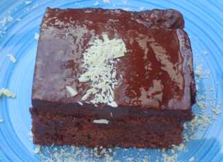 Ένα κομμάτι από εξαιρετικά υγρό κέικ σοκολάτας με πλούσιο σκούρο γλάσο, πασπαλισμένο με φιστίκι Αιγίνης.