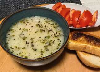 Ένα βαθύ πιάτο με κρεμώδη λευκή σούπα πατάτας, γαρνιρισμένο με φρέσκο μαϊντανό, τριμμένο τυρί και φρυγανισμένες φέτες ψωμιού.