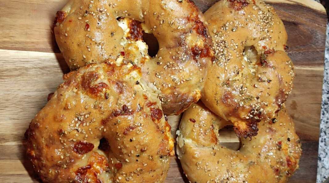 Πέντε στριφτές πίτες σε σχήμα σαλιγκαριού πάνω σε λαδόκολλα, πασπαλισμένες με σουσάμι και αλειμμένες με αρωματικό λάδι σκόρδου.