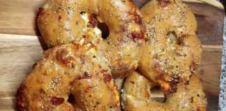 Πέντε στριφτές πίτες σε σχήμα σαλιγκαριού πάνω σε λαδόκολλα, πασπαλισμένες με σουσάμι και αλειμμένες με αρωματικό λάδι σκόρδου.