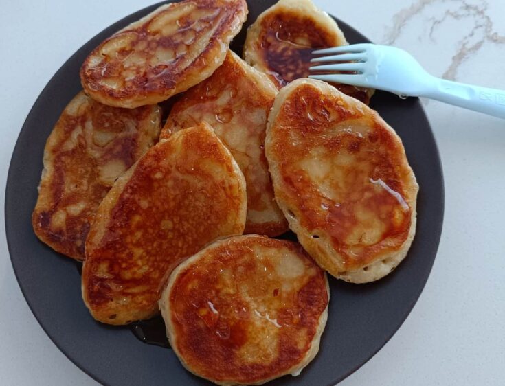 Μια στοίβα από χρυσαφένιες τηγανίτες, περιχυμένες με μέλι και πασπαλισμένες με κανέλα και καρύδια.