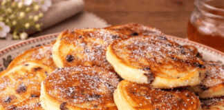 Μια στοίβα από αφράτες, χρυσαφένια τηγανίτες με λιωμένες σταγόνες σοκολάτας στο εσωτερικό τους, σερβιρισμένες σε ένα λευκό πιάτο.