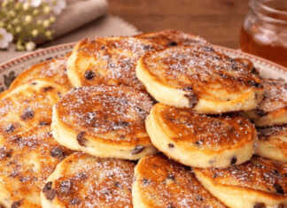 Μια στοίβα από αφράτες, χρυσαφένια τηγανίτες με λιωμένες σταγόνες σοκολάτας στο εσωτερικό τους, σερβιρισμένες σε ένα λευκό πιάτο.