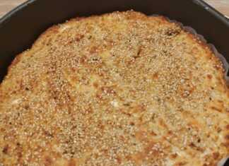 Μια ροδοκοκκινισμένη τυρόπιτα πασπαλισμένη με σουσάμι, κομμένη σε κομμάτια μέσα στο ταψί της.