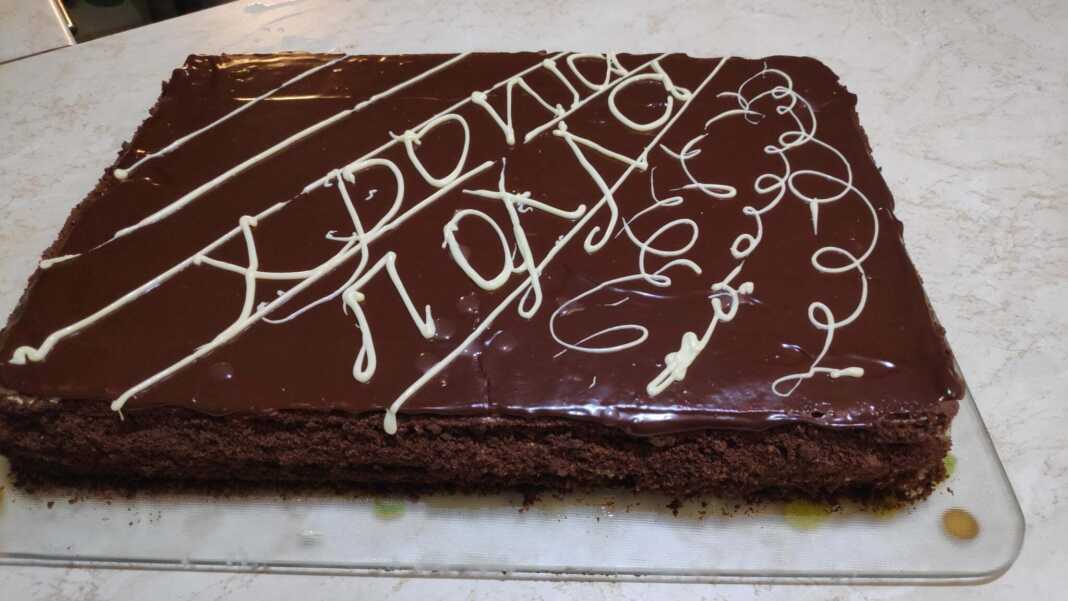 Μια ψηλή τούρτα με πολλές λεπτές στρώσεις ζύμης και κρέμας, καλυμμένη με τρίμματα ζύμης στα πλάγια και λιωμένη σοκολάτα στην κορυφή.