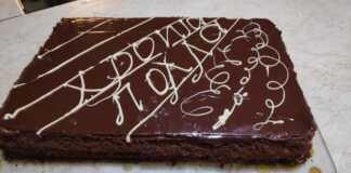 Μια ψηλή τούρτα με πολλές λεπτές στρώσεις ζύμης και κρέμας, καλυμμένη με τρίμματα ζύμης στα πλάγια και λιωμένη σοκολάτα στην κορυφή.