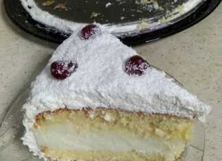 Μια εντυπωσιακή λευκή τούρτα καλυμμένη με πλούσιο ινδοκάρυδο, διακοσμημένη με κόκκινα κερασάκια σε χιονισμένο φόντο.