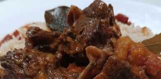 Μια πιατέλα με τρυφερό κρέας από ζυγούρι σε πλούσια κόκκινη σάλτσα, σερβιρισμένο πάνω σε σπυρωτό πιλάφι.