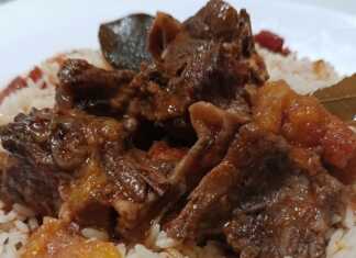 Μια πιατέλα με τρυφερό κρέας από ζυγούρι σε πλούσια κόκκινη σάλτσα, σερβιρισμένο πάνω σε σπυρωτό πιλάφι.