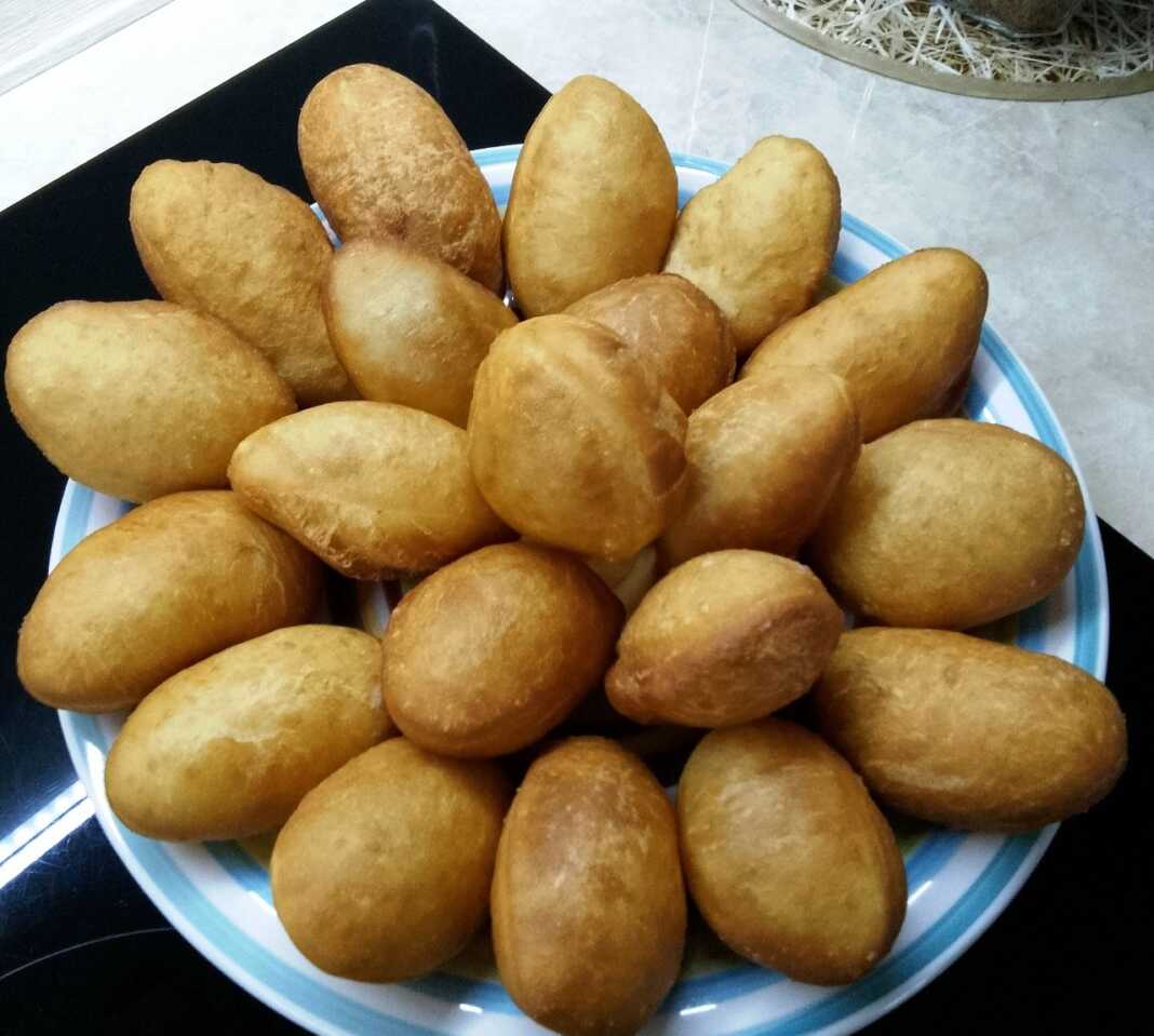 Μια στοίβα από χρυσαφένια, φουσκωτά και αέρινα ντονατσάκια πάνω σε μια πιατέλα, έτοιμα για σερβίρισμα.