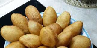 Μια στοίβα από χρυσαφένια, φουσκωτά και αέρινα ντονατσάκια πάνω σε μια πιατέλα, έτοιμα για σερβίρισμα.