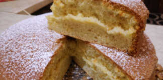 Ένα ψηλό και εξαιρετικά αφράτο κέικ πασπαλισμένο με άχνη ζάχαρη, κομμένο σε τριγωνικά κομμάτια.