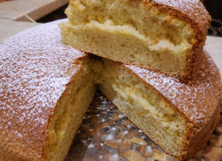 Ένα ψηλό και εξαιρετικά αφράτο κέικ πασπαλισμένο με άχνη ζάχαρη, κομμένο σε τριγωνικά κομμάτια.