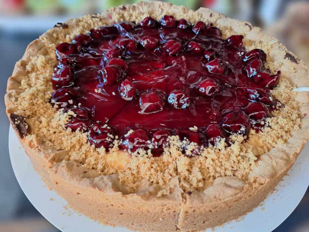 Πλούσιο κομμάτι ψητού cheesecake με παχιά στρώση κρέμας και κατακόκκινο γλυκό του κουταλιού βύσσινο να τρέχει στις πλευρές